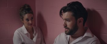 Movie still from “Robots” (2023), directed by Casper Christensen – A man and a woman are sitting in front of a wall; Close Up shot, Over the shoulder angle