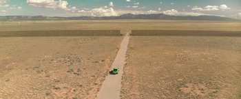 Movie still from “Robots” (2023), directed by Casper Christensen – An aerial view of a truck driving down a dirt road; Extreme Wide shot, Overhead angle