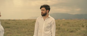 Movie still from “Robots” (2023), directed by Casper Christensen – A man in a white shirt is standing in a field; Close Up shot, Low angle