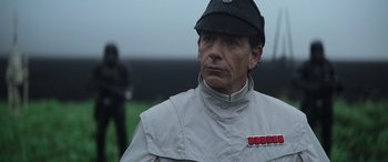 Movie still from “Rogue One: A Star Wars Story” (2016), directed by Gareth Edwards – A man wearing a white jacket and a black hat; Close Up shot, Over the shoulder angle