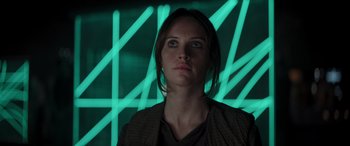 Movie still from “Rogue One: A Star Wars Story” (2016), directed by Gareth Edwards – A young woman is standing in front of a wall with green lights; Close Up shot, Low angle