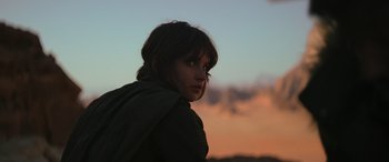 Movie still from “Rogue One: A Star Wars Story” (2016), directed by Gareth Edwards – A woman is standing in front of a sunset; Close Up shot, Low angle