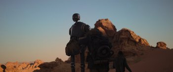 Movie still from “Rogue One: A Star Wars Story” (2016), directed by Gareth Edwards – A robot standing in front of a rock formation; Wide shot, Low angle
