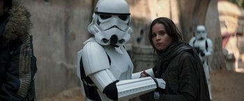 Movie still from “Rogue One: A Star Wars Story” (2016), directed by Gareth Edwards – A woman standing next to a star wars character; Medium shot, Over the shoulder angle