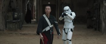 Movie still from “Rogue One: A Star Wars Story” (2016), directed by Gareth Edwards – A man in a black and white outfit and a stormtrooper in a black and white outfit; Medium shot, Over the shoulder angle