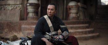 Movie still from “Rogue One: A Star Wars Story” (2016), directed by Gareth Edwards – A man sitting on the ground holding a rifle; Medium shot, Low angle