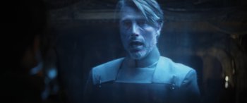 Movie still from “Rogue One: A Star Wars Story” (2016), directed by Gareth Edwards – A man with a beard is looking at the camera; Close Up shot, Over the shoulder angle