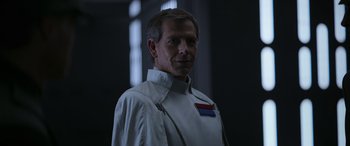 Movie still from “Rogue One: A Star Wars Story” (2016), directed by Gareth Edwards – A man in a white shirt is standing in the dark; Close Up shot, Over the shoulder angle