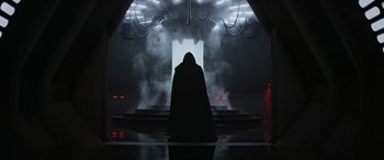 Movie still from “Rogue One: A Star Wars Story” (2016), directed by Gareth Edwards – A person in a hooded cloak standing in a dark room; Wide shot, Low angle
