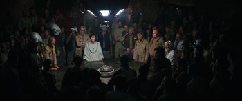 Movie still from “Rogue One: A Star Wars Story” (2016), directed by Gareth Edwards – A group of people standing around a cake; Wide shot, High angle