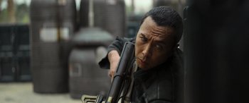 Movie still from “Rogue One: A Star Wars Story” (2016), directed by Gareth Edwards – A man holding a rifle in his hand; Close Up shot, Over the shoulder angle