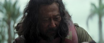 Movie still from “Rogue One: A Star Wars Story” (2016), directed by Gareth Edwards – A person with long hair and a beard; Close Up shot, Over the shoulder angle
