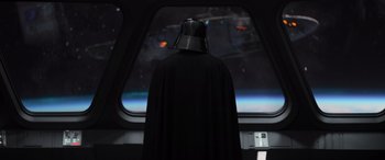 Movie still from “Rogue One: A Star Wars Story” (2016), directed by Gareth Edwards – A man in a darth vader costume looking out of a window; Medium shot, Over the shoulder angle