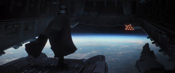 Movie still from “Rogue One: A Star Wars Story” (2016), directed by Gareth Edwards – A man in a darth vader costume looking out at the earth; Wide shot, Overhead angle