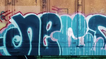 Movie still from “Rolling Like Thunder” (2021), directed by Roger Gastman – A train car covered in graffiti on the side of the road; Extreme Close Up shot, Low angle
