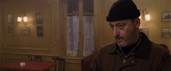 Movie still from “Ronin” (1998), directed by John Frankenheimer – A man wearing a black hat and a brown jacket; Close Up shot, Over the shoulder angle