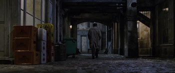 Movie still from “Ronin” (1998), directed by John Frankenheimer – A man walking down a street with a garbage can; Wide shot, High angle
