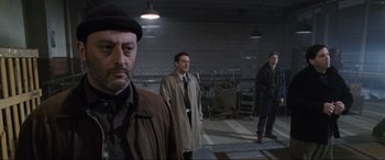 Movie still from “Ronin” (1998), directed by John Frankenheimer – A group of men standing next to each other in a building; Medium shot, Over the shoulder angle
