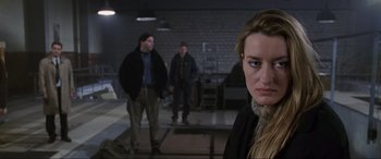 Movie still from “Ronin” (1998), directed by John Frankenheimer – A woman standing next to two men in a room; Medium shot, Over the shoulder angle