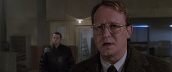 Movie still from “Ronin” (1998), directed by John Frankenheimer – A man in a suit and tie standing next to another man in a suit and tie; Close Up shot, Low angle