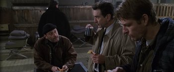 Movie still from “Ronin” (1998), directed by John Frankenheimer – A group of people sitting at a table eating food; Medium shot, Over the shoulder angle