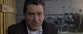 Movie still from “Ronin” (1998), directed by John Frankenheimer – A person wearing a suit and tie; Close Up shot, Over the shoulder angle
