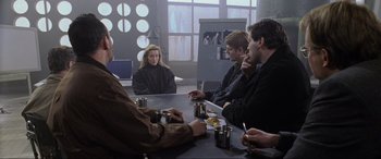 Movie still from “Ronin” (1998), directed by John Frankenheimer – A group of people sitting around a table; Medium shot, Over the shoulder angle