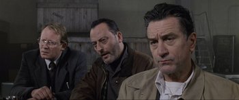 Movie still from “Ronin” (1998), directed by John Frankenheimer – A group of men sitting next to each other in a room; Close Up shot, Low angle