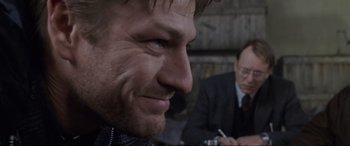 Movie still from “Ronin” (1998), directed by John Frankenheimer – A man in a suit and a man in a suit and tie; Close Up shot, Over the shoulder angle