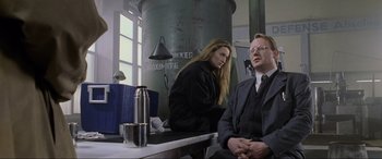 Movie still from “Ronin” (1998), directed by John Frankenheimer – A man and a woman sitting in front of a table; Medium shot, Low angle