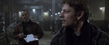 Movie still from “Ronin” (1998), directed by John Frankenheimer – A man in a jacket is standing next to another man in a brown jacket; Close Up shot, Over the shoulder angle