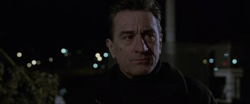 Movie still from “Ronin” (1998), directed by John Frankenheimer – A person wearing a black jacket; Close Up shot, Over the shoulder angle