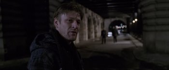 Movie still from “Ronin” (1998), directed by John Frankenheimer – A man standing in the dark in front of a tunnel; Medium shot, Over the shoulder angle