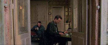 Movie still from “Ronin” (1998), directed by John Frankenheimer – Two men sitting at a kitchen table working on laptops; Wide shot, Low angle