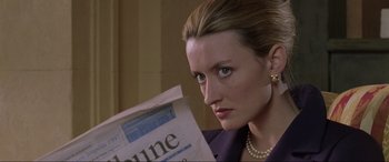 Movie still from “Ronin” (1998), directed by John Frankenheimer – A woman in a purple jacket is holding a newspaper; Close Up shot, Over the shoulder angle