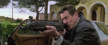 Movie still from “Ronin” (1998), directed by John Frankenheimer – A man holding a gun in his hands; Close Up shot, Low angle