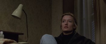 Movie still from “Ronin” (1998), directed by John Frankenheimer – A woman sitting in front of a wall looking to her left; Close Up shot, Low angle