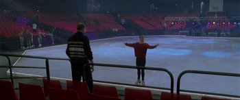 Movie still from “Ronin” (1998), directed by John Frankenheimer – A man standing on a stage in front of an audience; Extreme Wide shot, Low angle