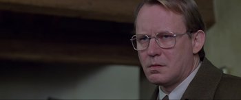 Movie still from “Ronin” (1998), directed by John Frankenheimer – An older man wearing glasses and a suit; Close Up shot, Low angle