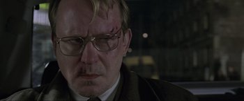 Movie still from “Ronin” (1998), directed by John Frankenheimer – A person wearing a suit and glasses; Close Up shot, Low angle