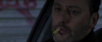 Movie still from “Ronin” (1998), directed by John Frankenheimer – A person in a car smoking a cigarette; Close Up shot, Low angle