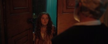 Movie still from “Rosaline” (2022), directed by Karen Maine – A woman standing in front of a mirror looking at herself in the mirror; Medium shot, Over the shoulder angle