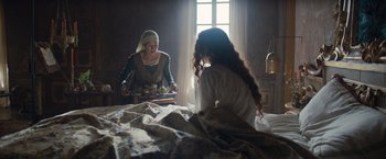 Movie still from “Rosaline” (2022), directed by Karen Maine – Two women sitting on a bed in front of a window; Medium shot, Over the shoulder angle