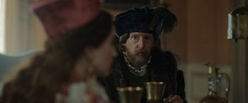 Movie still from “Rosaline” (2022), directed by Karen Maine – A man wearing a fur coat and a fur hat; Close Up shot, Over the shoulder angle