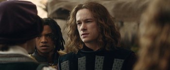 Movie still from “Rosaline” (2022), directed by Karen Maine – A man with long hair and a sweater on; Close Up shot, Over the shoulder angle