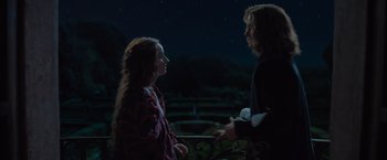Movie still from “Rosaline” (2022), directed by Karen Maine – A man and a woman standing next to each other in front of a night sky; Medium shot, Over the shoulder angle