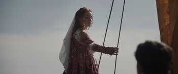 Movie still from “Rosaline” (2022), directed by Karen Maine – A young girl dressed in medieval clothing holding a bow and arrow; Medium shot, Low angle
