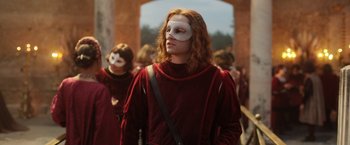 Movie still from “Rosaline” (2022), directed by Karen Maine – A person with a white mask and a red outfit; Medium shot, Over the shoulder angle