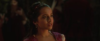 Movie still from “Rosaline” (2022), directed by Karen Maine – A young woman in a red dress looking to her left; Close Up shot, Over the shoulder angle