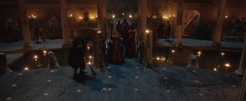 Movie still from “Rosaline” (2022), directed by Karen Maine – A group of people standing in a room with candles; Extreme Wide shot, High angle